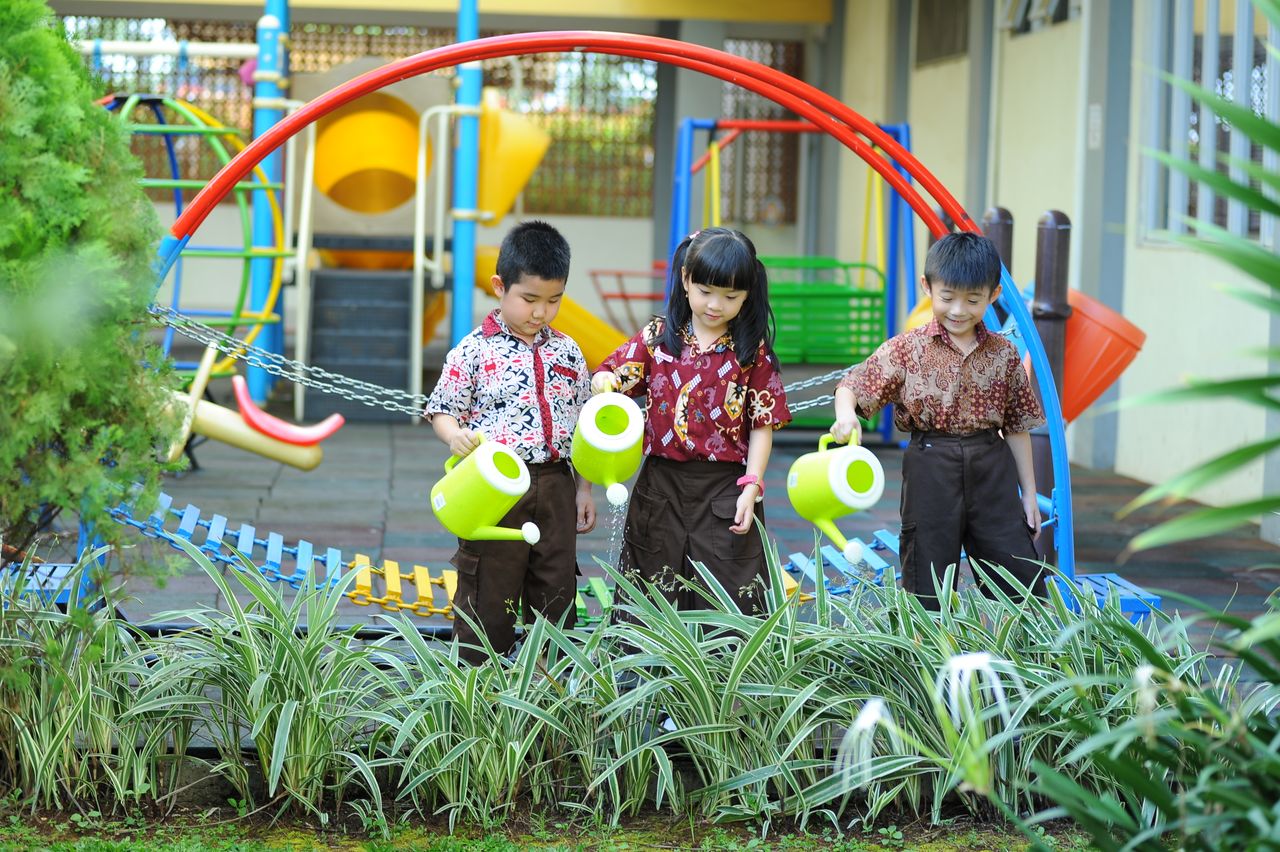 Group of children enjoying gardening in a playground setting.