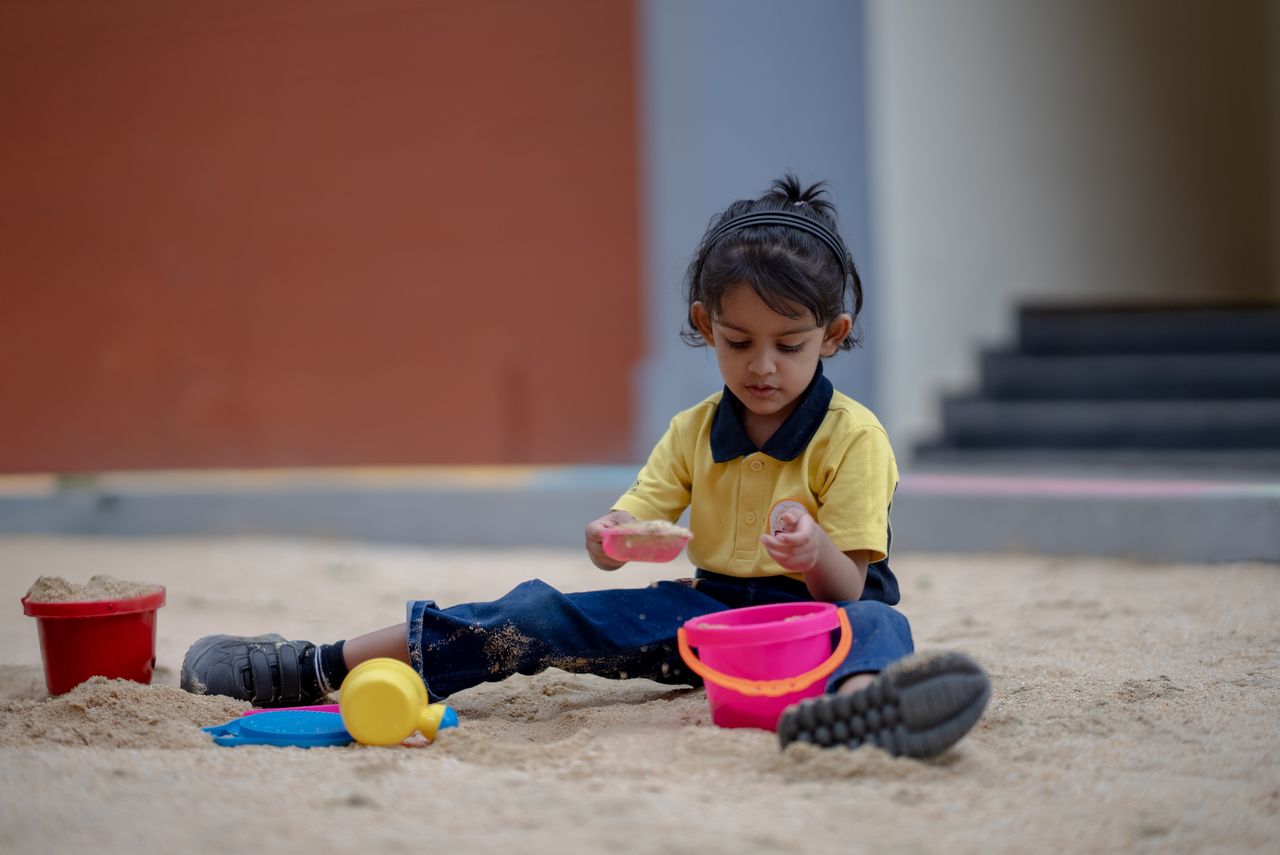A young child plays in the sandbox, exploring creativity with sand toys outdoors.