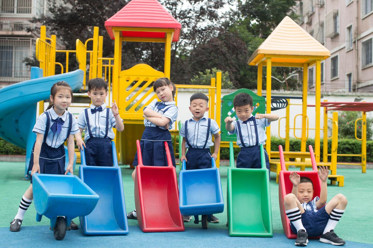Group of children in uniform playing with carts at a vibrant playground.